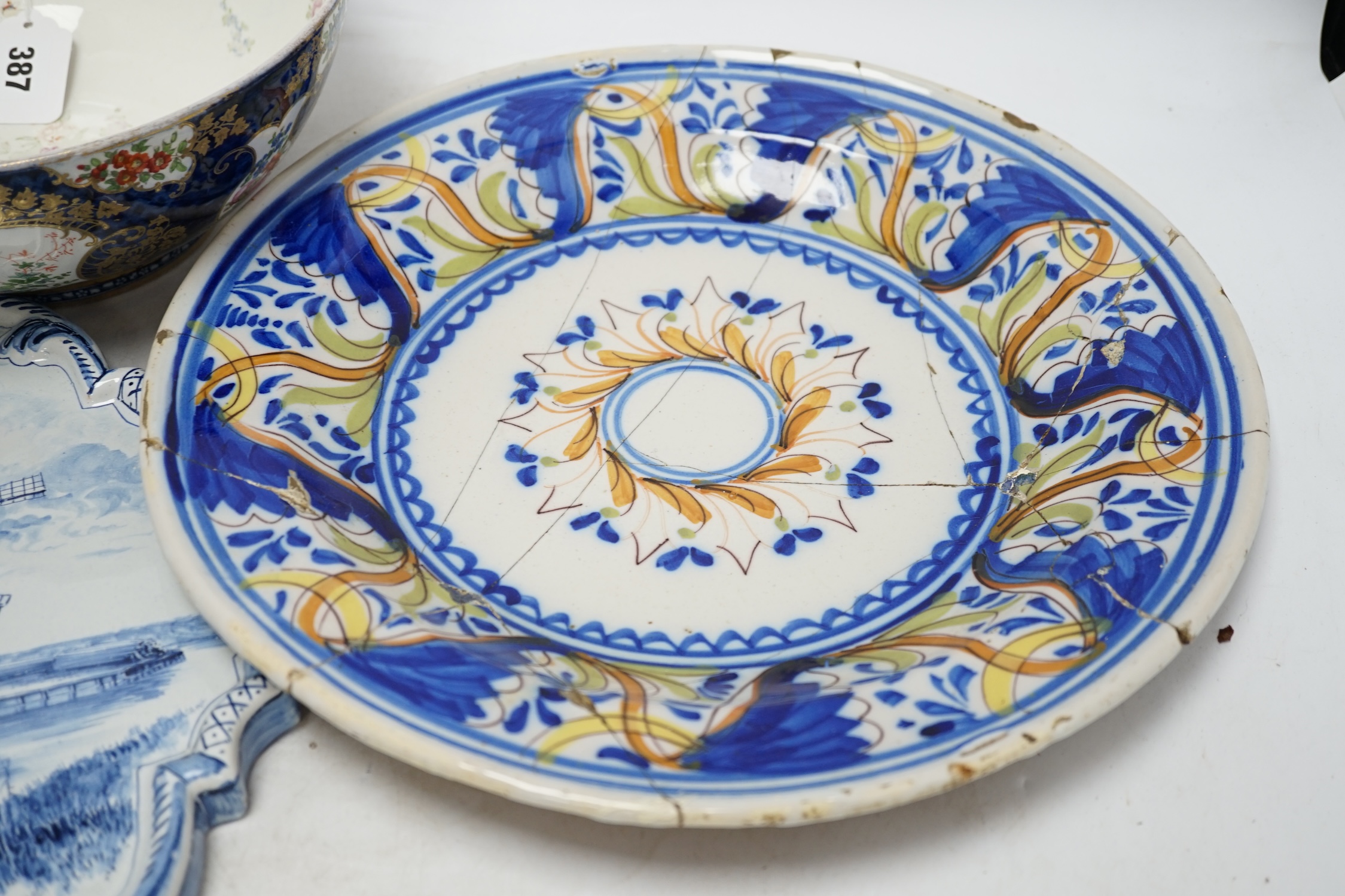 A Delft blue and white plaque, two continental tin-glazed dishes, one signed V.M.D, and a Booths scale-blue bowl, largest 35cm in diameter. Condition - largest dish poor, others fair